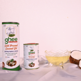 Two Containers Of Ghee Store Cold Pressed Coconut Oil Next To A Glass Bowl Filled With Coconut Oil And A Halved Coconut On A White Surface.