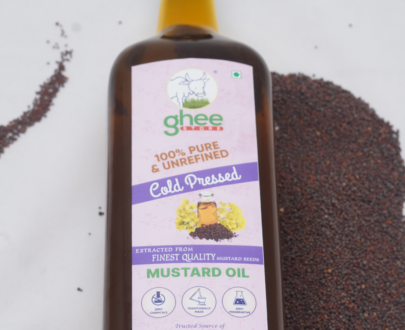 Bottle of GheeStore 100% pure and unrefined cold-pressed mustard oil with mustard seeds in the background.