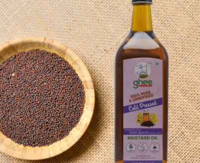 Bottle of 100% pure, unrefined cold-pressed mustard oil next to a bowl of mustard seeds on a burlap surface.