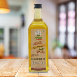 Bottle Of Cold-Pressed Groundnut Oil From Ghee Store With A Label Stating &Quot;100% Pure &Amp; Unrefined&Quot; On A Wooden Surface With A Blurred Background.
